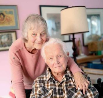 Male client seated with female caregiver standing behind